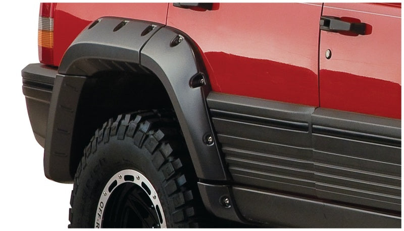 Red truck with black tire cover and bushwacker fender flares on a jeep grand cherokee