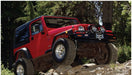 Black pocket style fender flares on red jeep wrangler driving rocky trail