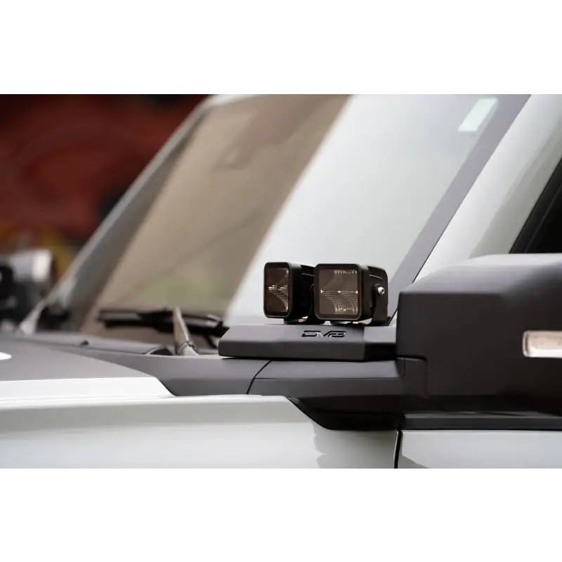 White car rear view mirror with DV8 Ford Bronco A-Pillar Pod Light Mounts.