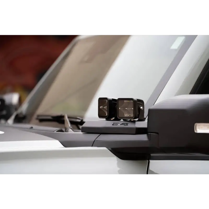 White car rear view mirror with DV8 Ford Bronco A-Pillar Pod Light Mounts.
