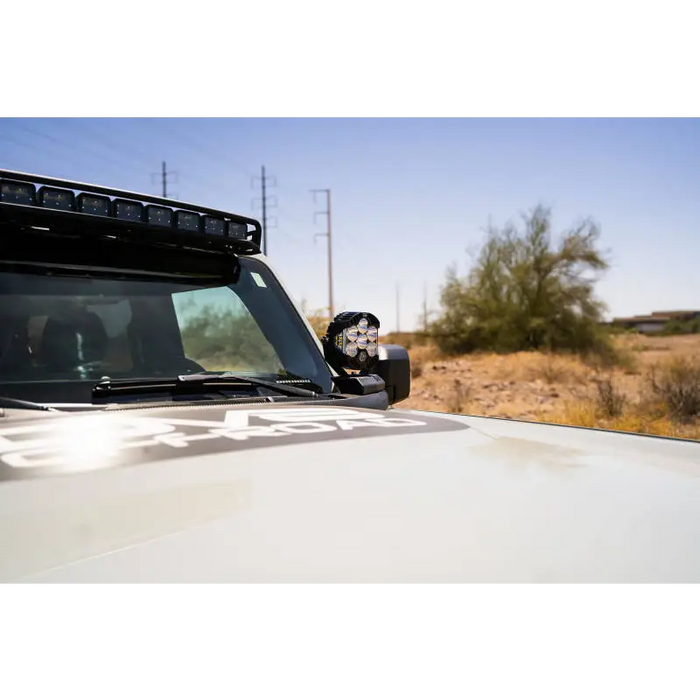 White truck with black roof rack showcasing DV8 21-22 Ford Bronco A-Pillar Pod Light Mounts.