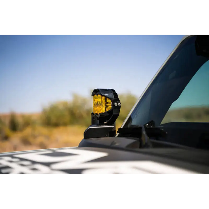 DV8 21-22 Ford Bronco A-Pillar Pod Light Mounts featuring a yellow pod light on a truck.