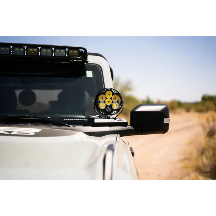 White truck with yellow and black emblem displaying DV8 Bronco A-Pillar Pod Light Mounts