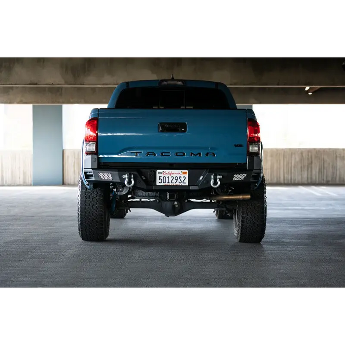 Blue truck parked in garage featuring DV8 Offroad 16-23 Toyota Tacoma MTO Series Rear Bumper.