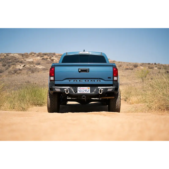 Blue truck rear end on dirt road with DV8 Offroad MTO Series Rear Bumper