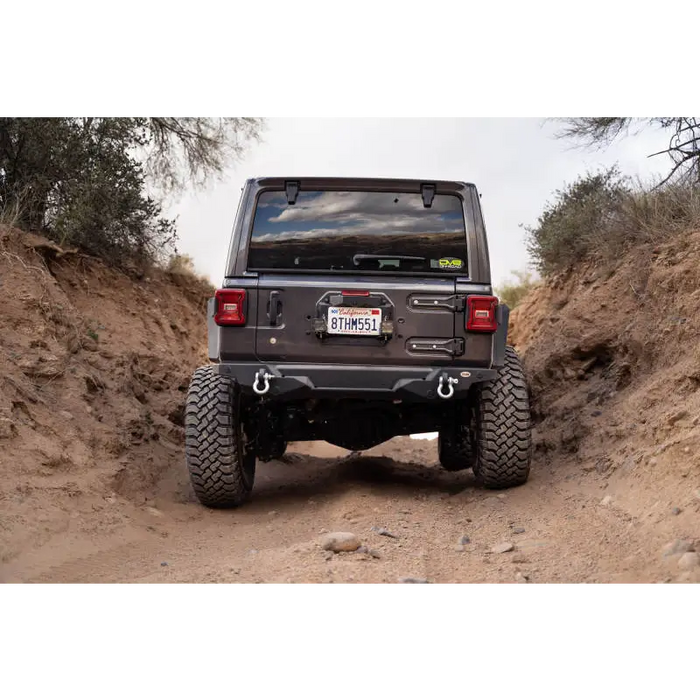 Jeep driving down dirt road with spare tire delete kit.