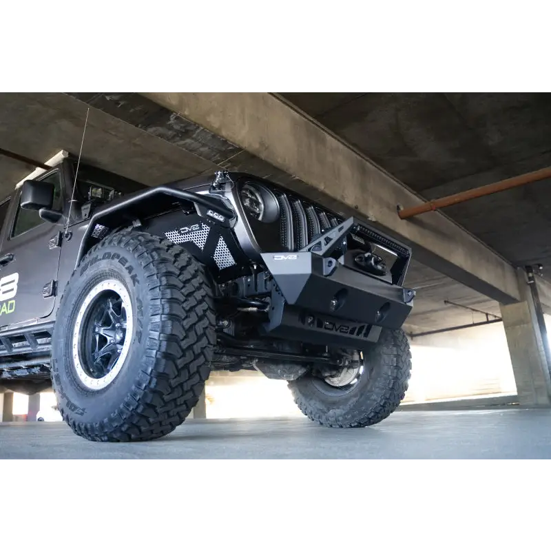 Black Jeep Wrangler JL/JT with large tire, featuring DV8 Offroad Front Bumper Sway Bar Disconnect Motor Skid Plate