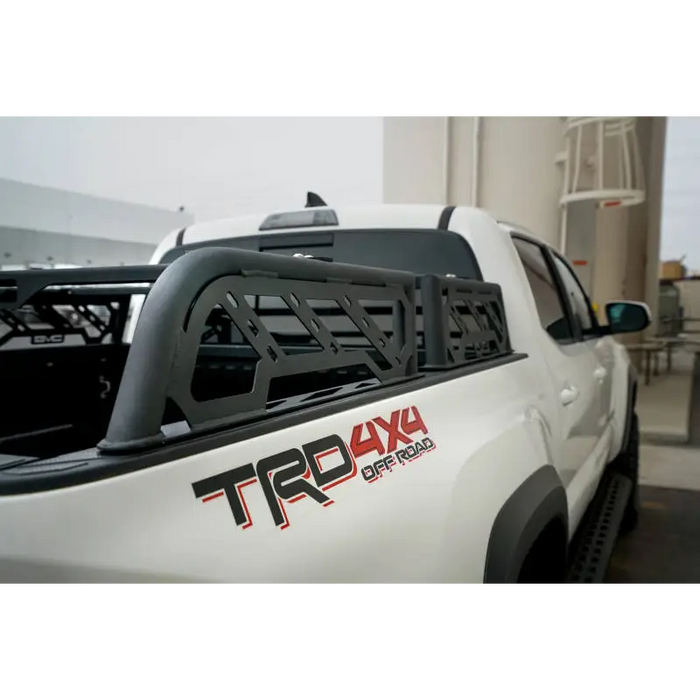 White truck with black and red decal on DV8 Offroad bed rack for Toyota Tacoma overland.