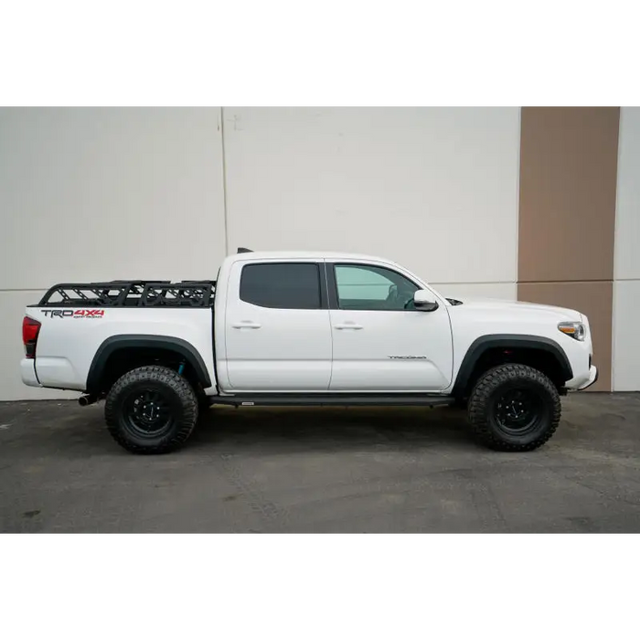 White truck with black rim and tire cover on DV8 Offroad bed rack - Toyota Tacoma overland.