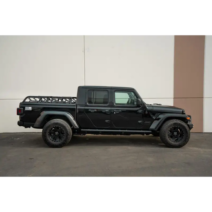 DV8 Offroad black Jeep Gladiator JT / Toyota Tacoma Overland bed rack with black bumper and wheels.