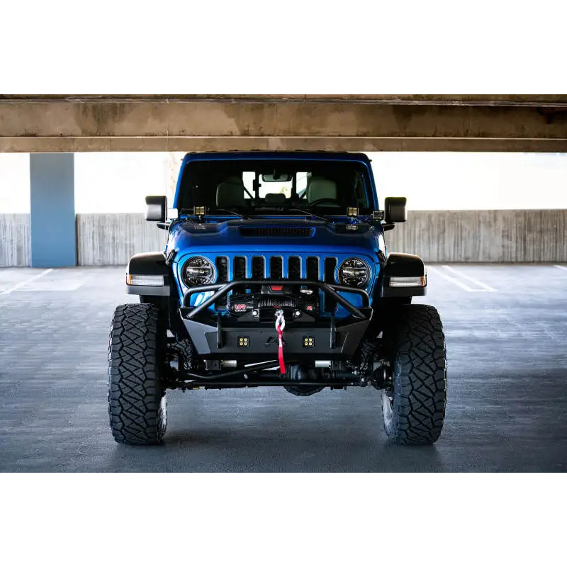Blue Jeep parked under bridge in parking lot with dual pod light mounts.