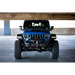 Blue Jeep parked under bridge in parking lot with dual pod light mounts.