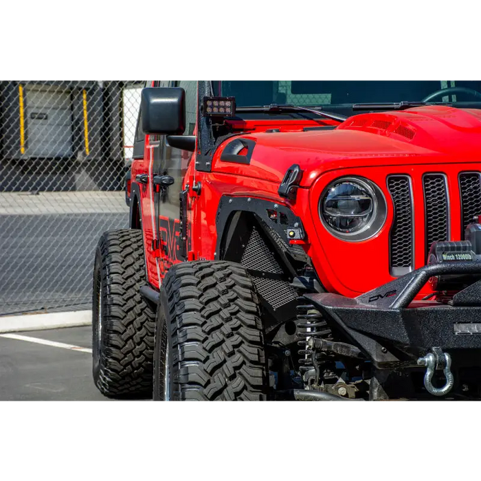 Red Jeep parked in parking lot with fence: DV8 Offroad 2018+ Jeep JL Fender Delete Kit