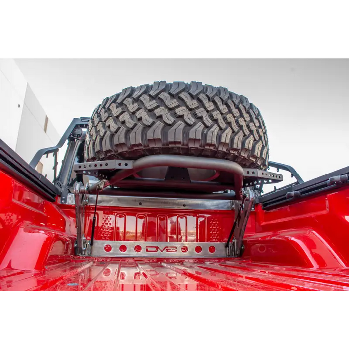DV8 Offroad 2019+ Jeep Gladiator In-Bed Adjustable Tire Carrier with large tire on truck