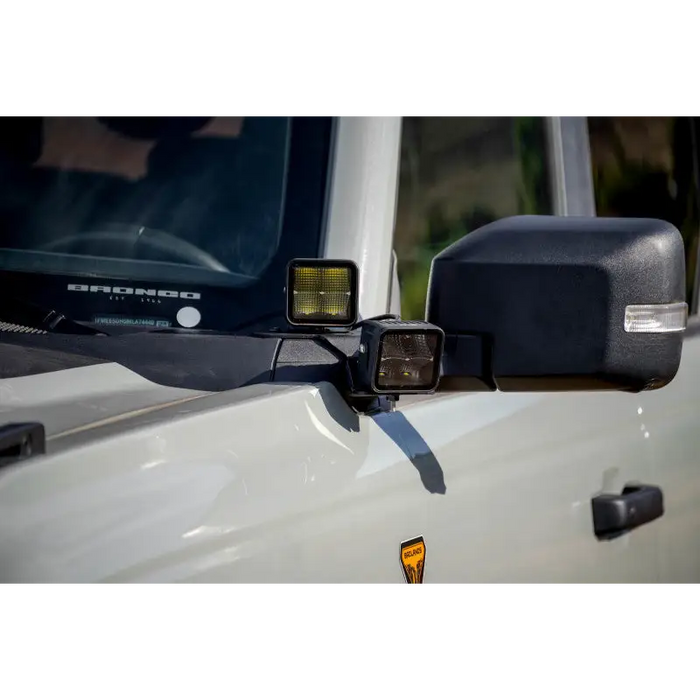 White truck with mirror on DV8 Offroad’s 2021 Ford Bronco A Pillar Dual Light Pod Drop Mounts.