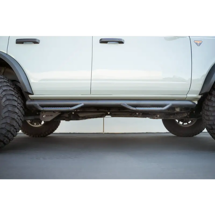 White truck with large tire, DV8 Offroad 2021 Ford Bronco Trailing Arm Skid Plates.