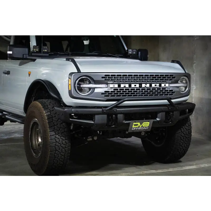 White truck with big bumper and license plate relocation bracket - DV8 Offroad Ford Bronco.