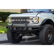 White truck with big front bumper, license plate relocation bracket for Ford Bronco.
