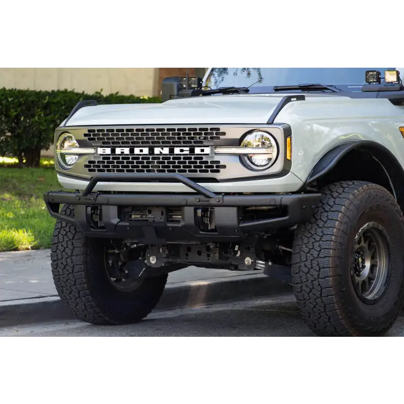White truck with big front bumper, license plate relocation bracket for Ford Bronco.