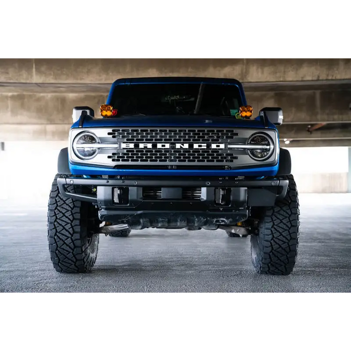 Blue lifted truck with black bumper, DV8 Offroad Ford Bronco Factory Front Bumper License Relocation Bracket.