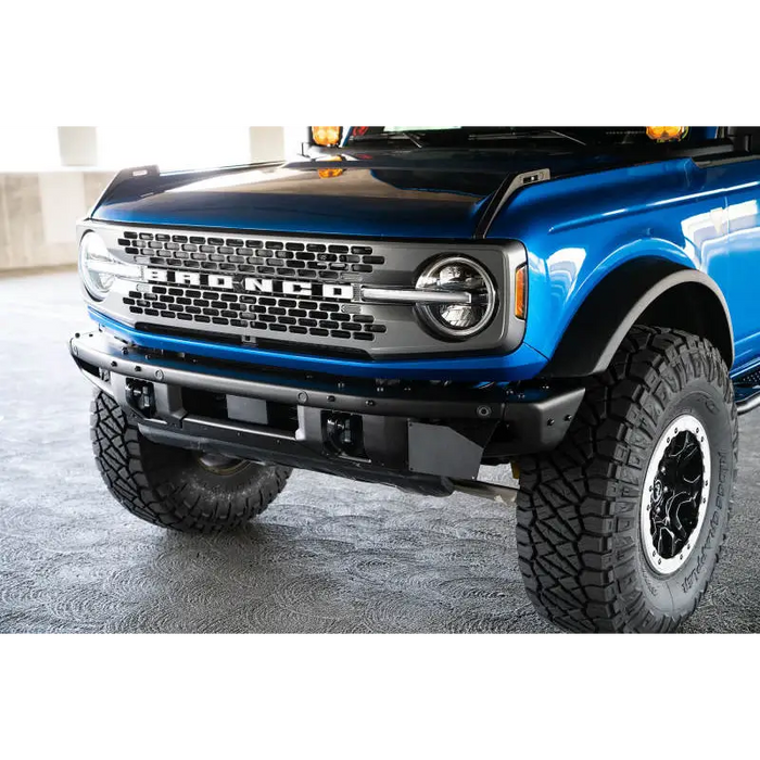 Blue lifted truck with black bumper featuring DV8 Offroad 21-22 Ford Bronco Factory Front Bumper License Relocation Bracket.