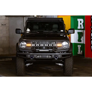Black Land Rover parked in garage next to DV8 Offroad 21-22 Ford Bronco Factory Modular Front Bumper Bull Bar.