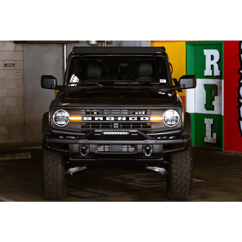 Black Land Rover parked in garage next to DV8 Offroad 21-22 Ford Bronco Factory Modular Front Bumper Bull Bar.