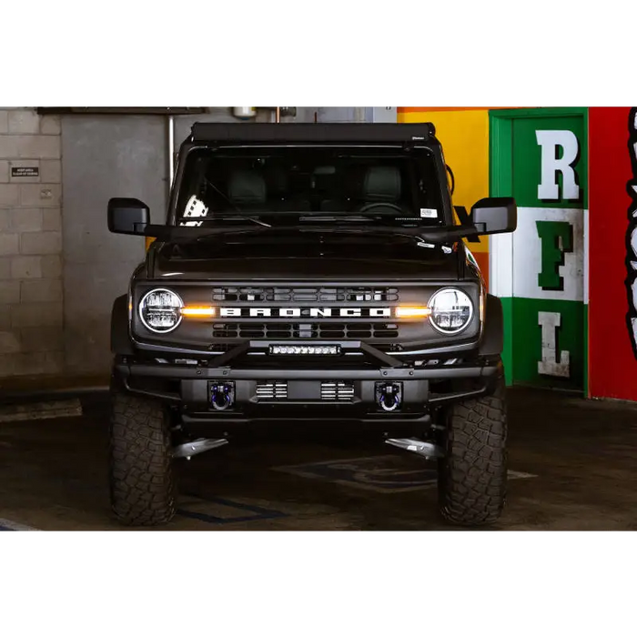 Black Land Rover parked in garage next to DV8 Offroad 21-22 Ford Bronco Factory Modular Front Bumper Bull Bar.