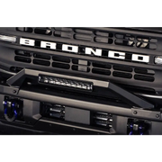 Close up of DV8 Offroad 21-22 Ford Bronco Factory Modular Front Bumper Bull Bar with chrome grille and blue light.