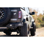 Black truck with big tire on road next to DV8 Offroad 21-22 Ford Bronco MTO Series Rear Bumper