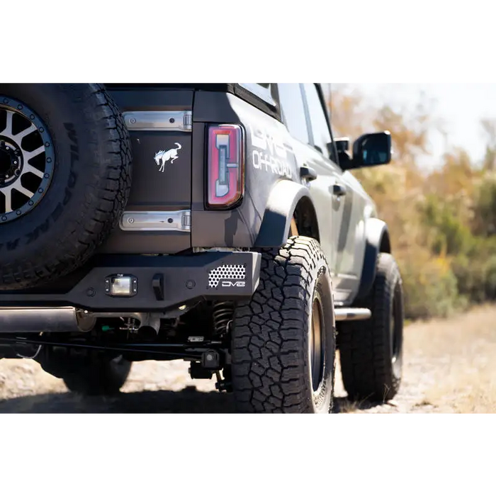 Black truck with big tire on road next to DV8 Offroad 21-22 Ford Bronco MTO Series Rear Bumper