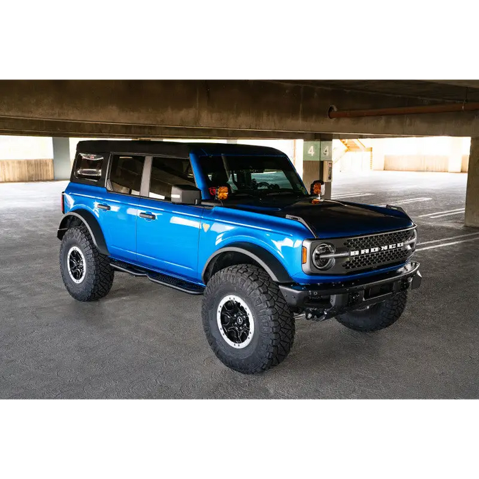 DV8 Offroad Ford Bronco OE Plus Series Side Steps with blue truck parked under a bridge in a parking lot