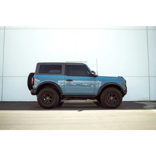 Blue truck parked in front of building with DV8 Offroad pinch weld covers for Ford Bronco.