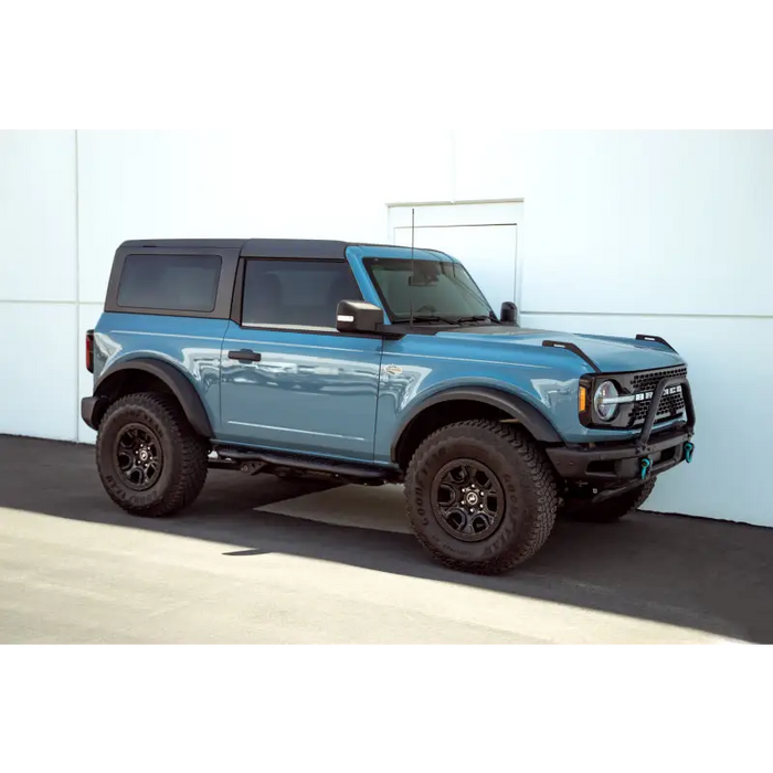 Blue Ford Bronco truck parked in front of white wall, DV8 Offroad pinch weld covers.