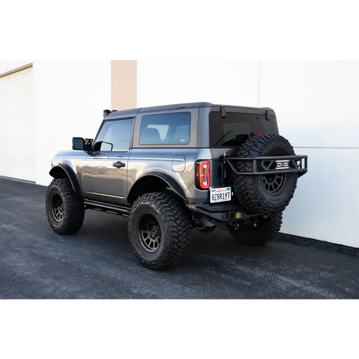Offroad black Jeep parked in front of building beside DV8 rock sliders for Ford Bronco.