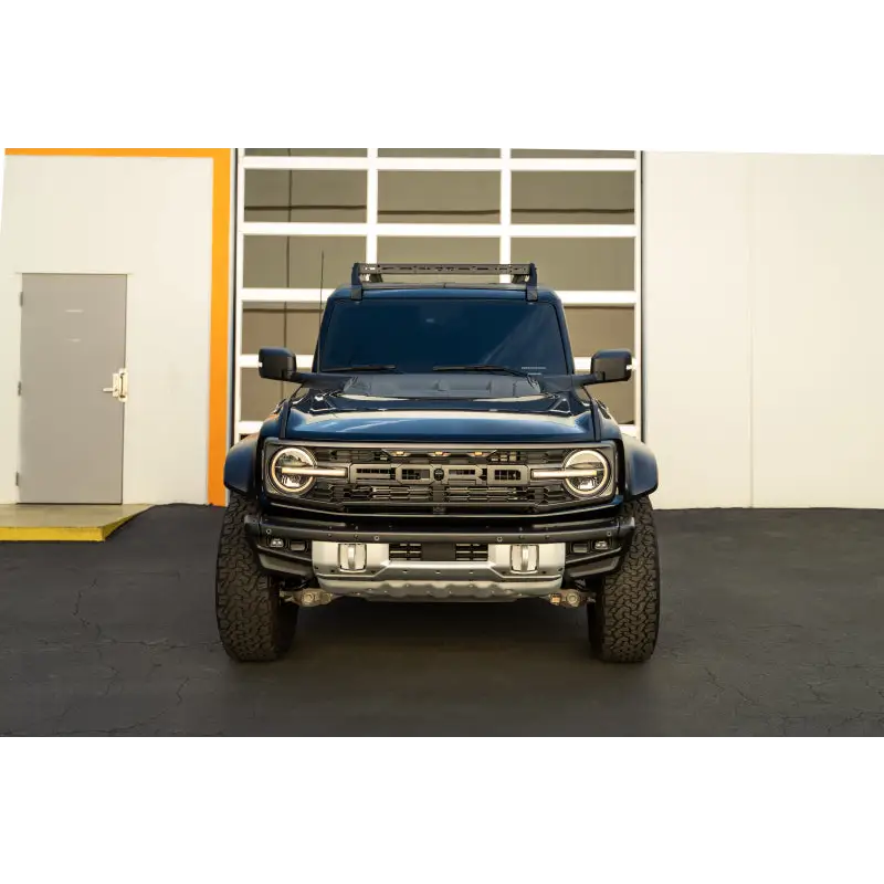 Blue truck parked in front of building with DV8 Offroad hard top roof rack and light bar mount.