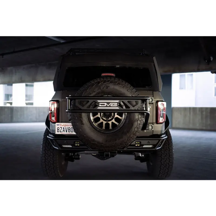 Black Jeep parked in parking garage with spare tire guard by DV8 Offroad.