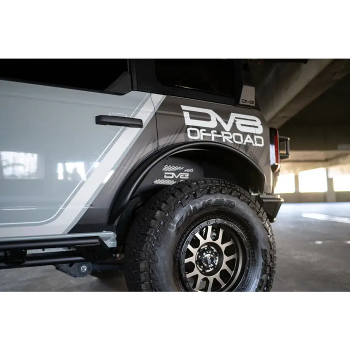 White truck with black tire cover - DV8 Offroad Ford Bronco fender flares.