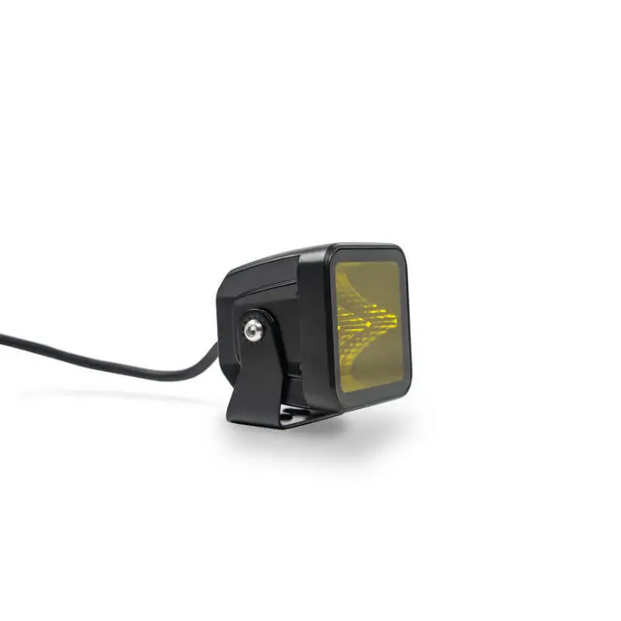 DV8 Offroad 3in Elite Series LED Amber Pod Light on a black car rear view mirror with yellow light