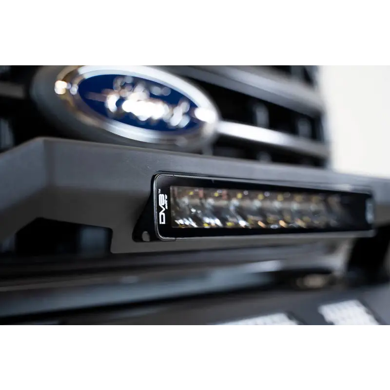 Close up of car grille with Ford logo on DV8 Offroad Elite Series 13in Light Bar 45W Flood/Spot LED.