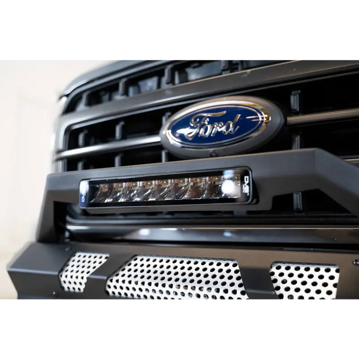 Close up of Ford truck grill with blue Ford logo on DV8 Offroad Elite Series 13in Light Bar 45W Flood/Spot LED.