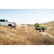 DV8 Offroad Elite Series D-Ring Shackles - Pair (Black) on hill with truck in background
