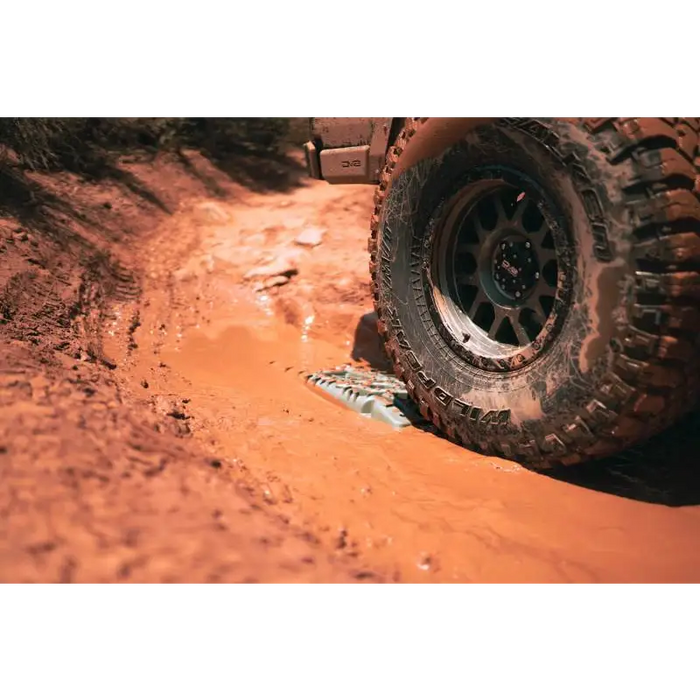 DV8 Offroad Recovery Traction Boards navigating through mud on a dirt road.