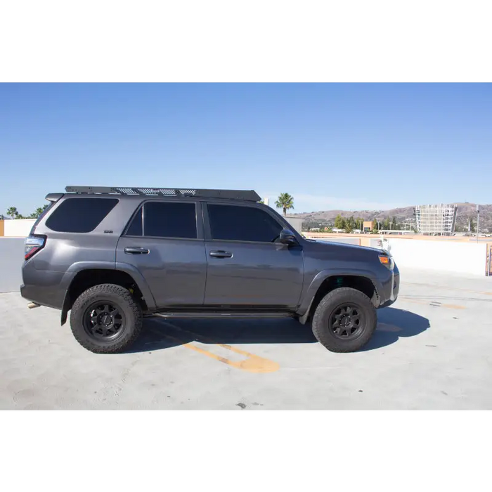 Gray Toyota SUV parked in a parking lot beside Go Rhino 10-23 Toyota 4Runner Ceros Low Profile Roof Rack.