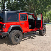 Jeep wrangler with electric running board kit parked in dirt.