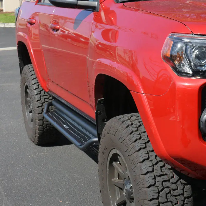 Red truck parked in parking lot next to go rhino dominator extreme d1 side steps - tex blk - 80in