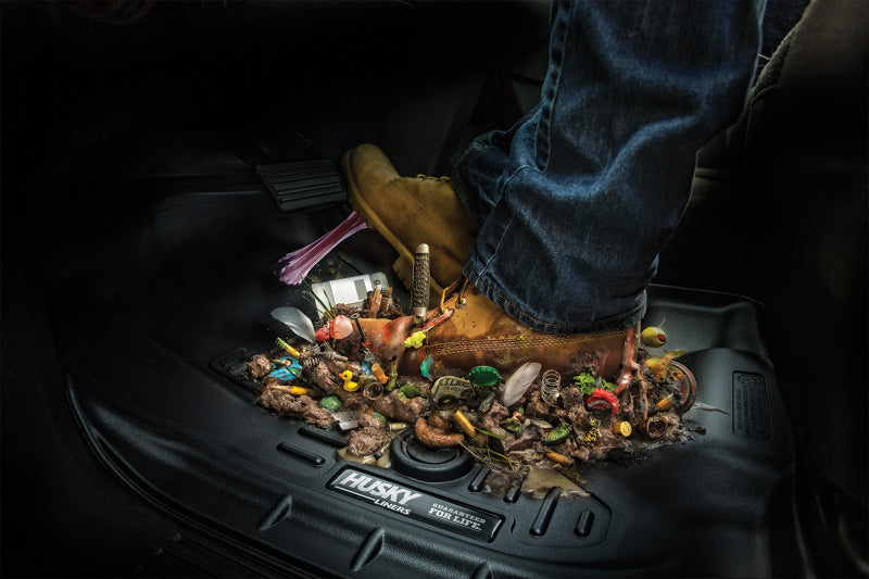 Person putting trash into jeep wrangler’s trunk with husky liners cargo liner