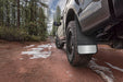 Universal 12in wide black rubber rear mud flaps on dirt road for trucks