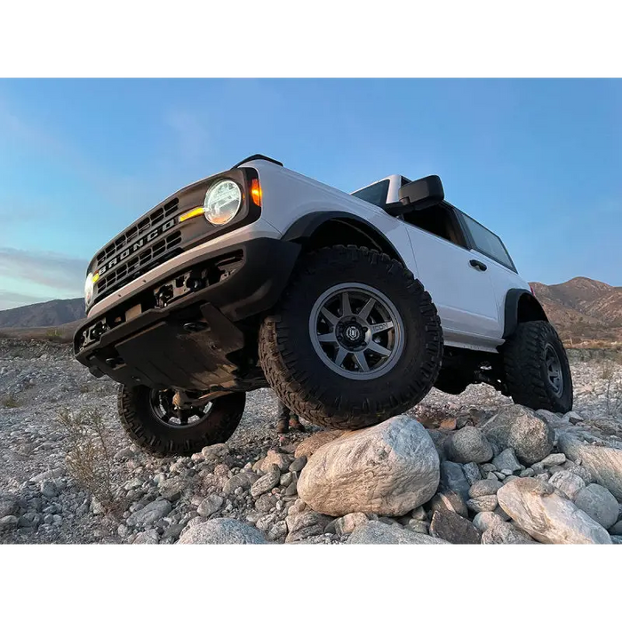 White Ford Bronco truck parked on desert rocks with ICON 2021+ 3in Lift C/O Spacer Kit