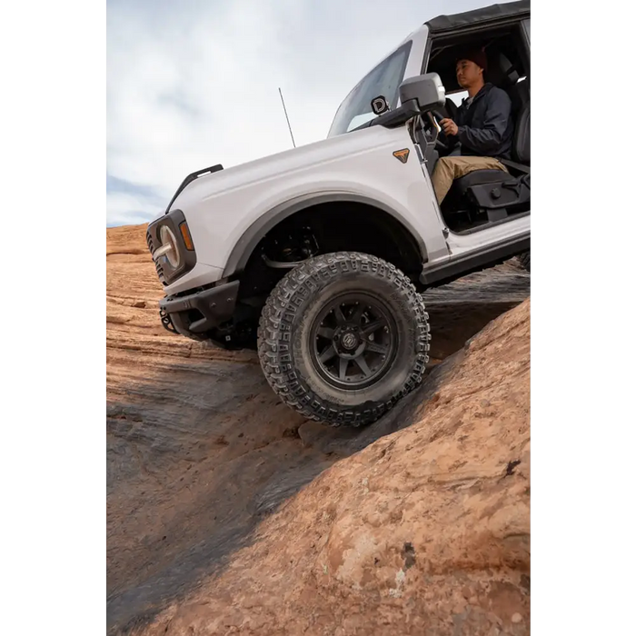 Man driving white truck down rocky hill in ICON Rebound Pro 17x8.5 6x5.5 wheel